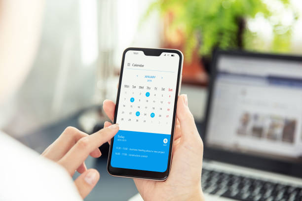 la femme d'affaires pointe l'écran de smartphone et vérifie le calendrier sur l'application. application à l'écran créée dans le programme graphique - agenda téléphone photos et images de collection